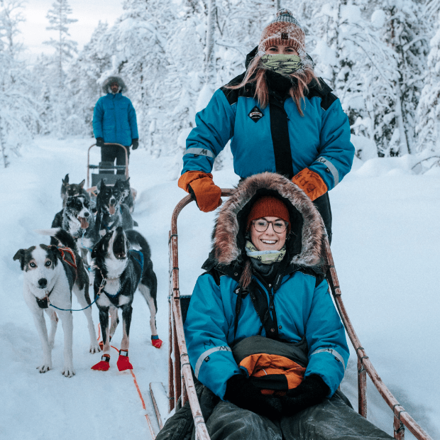 Happy tourists on husky safari in Rovaniemi, Finnish Lapland
