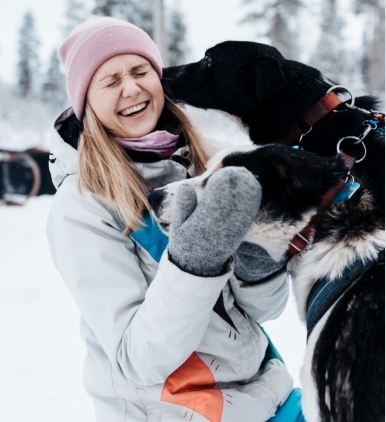 Woman laughing with two huskies in Lapland, Finland
