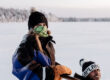 Two guests enjoying a husky tour on a frozen lake