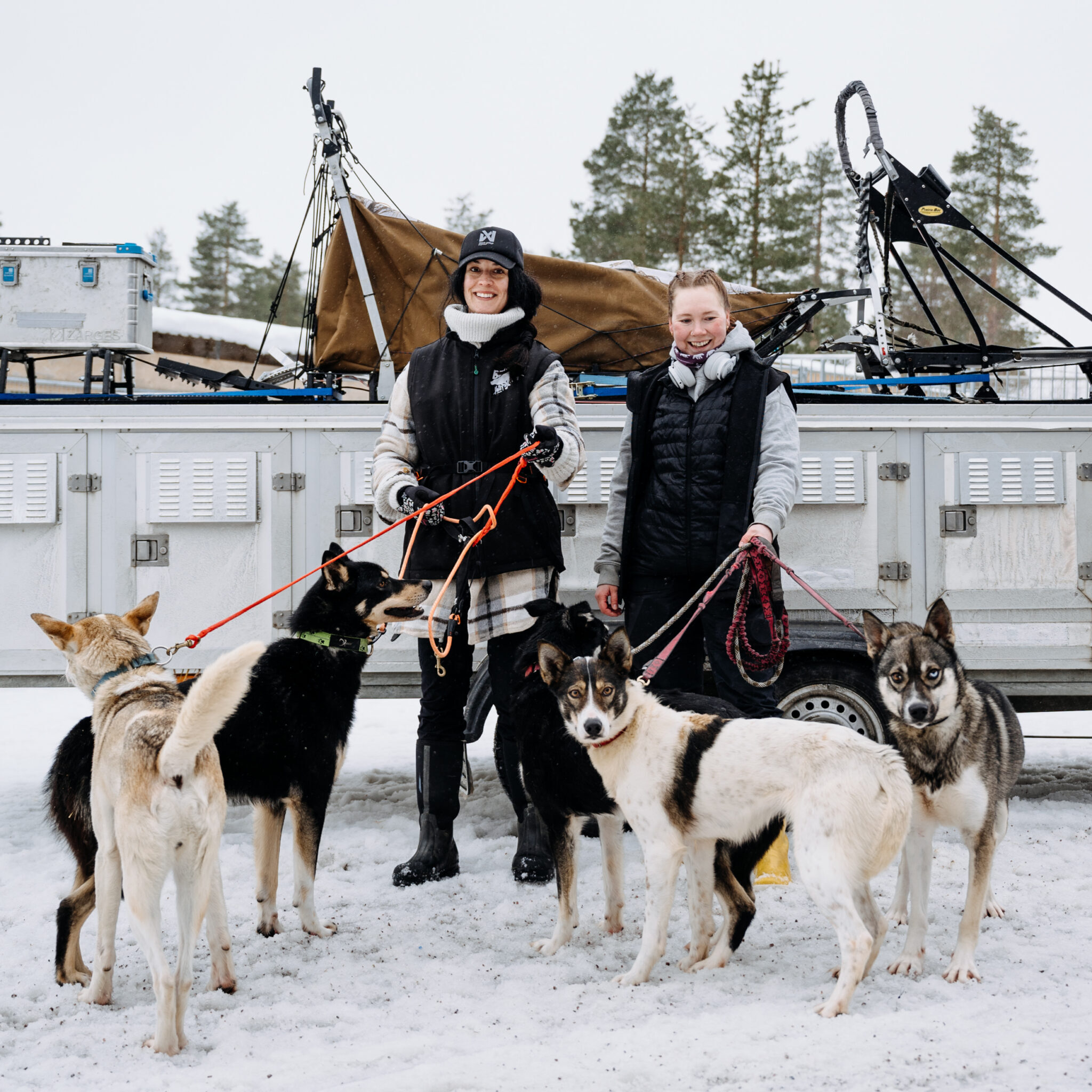 Two staff members getting ready for a race posing with their race team dogs