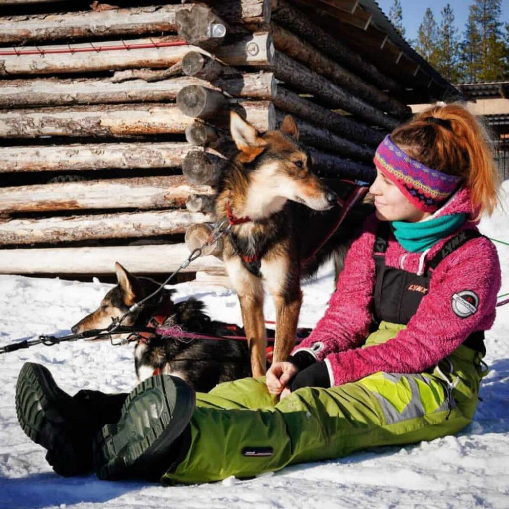 Cristina and the Alaskan husky Tipper in front of the sled shed