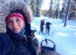 Cristina driving a team of dogs through the snowy forest