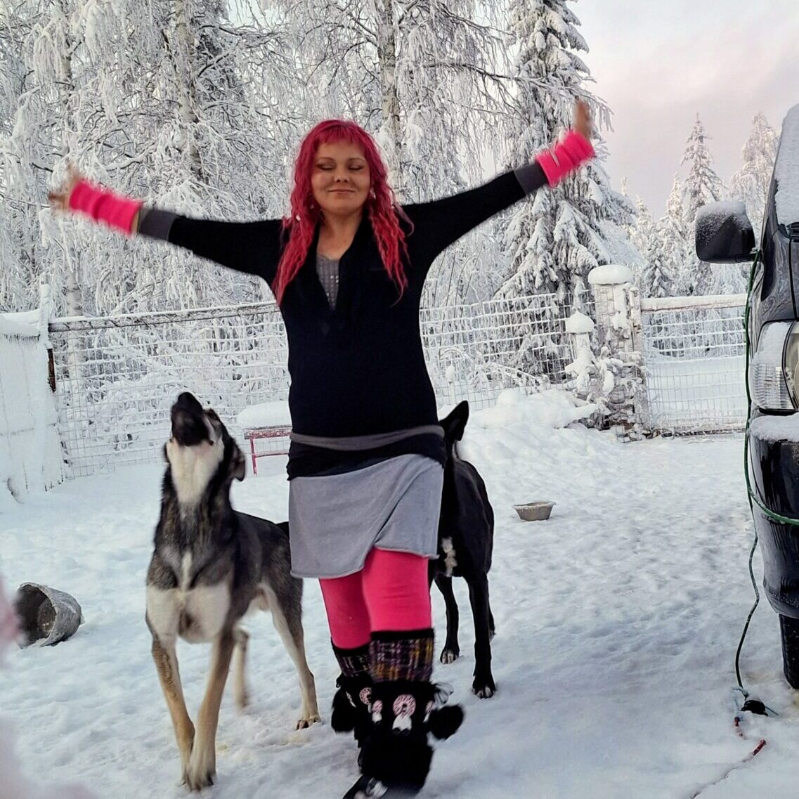 Jessica walking with two of her Alaskan Huskies in a snowy landscape