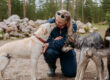 A guest cuddling with two Alaskan Huskies